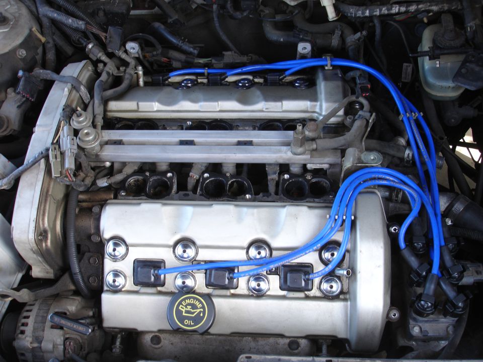Engine bay with V6 engine, blue spark plug wires, and an oil cap