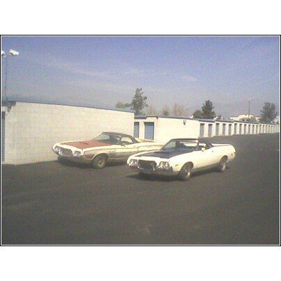 1972 Ford Ranchero - Two Ford Rancheros from the early 1970s are parked side-by-side in front of a row of storage units.
