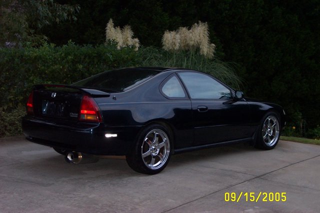 Black Honda Prelude coupe parked on a concrete driveway, rear quarter view