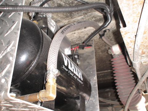 1993 Ford C-350 (Centurion Conversions) - Close-up of a VIAIR air compressor tank and its plumbing, with a red bellows cover visible.