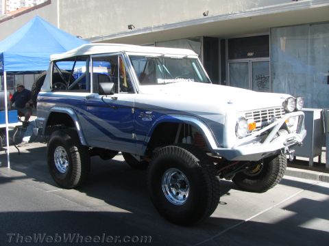 1990 Ford Bronco - lifted blue and white early Ford Bronco with a white hardtop and tube bumper parked at an outdoor event.