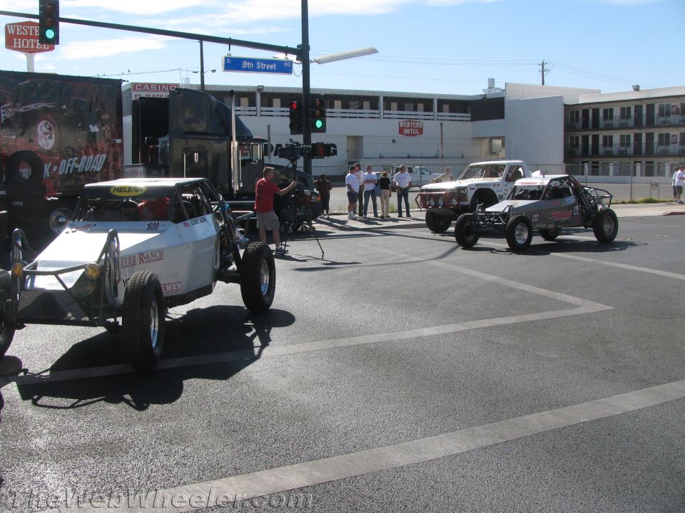 Off-road buggies and trucks staged at an intersection near 8th Street