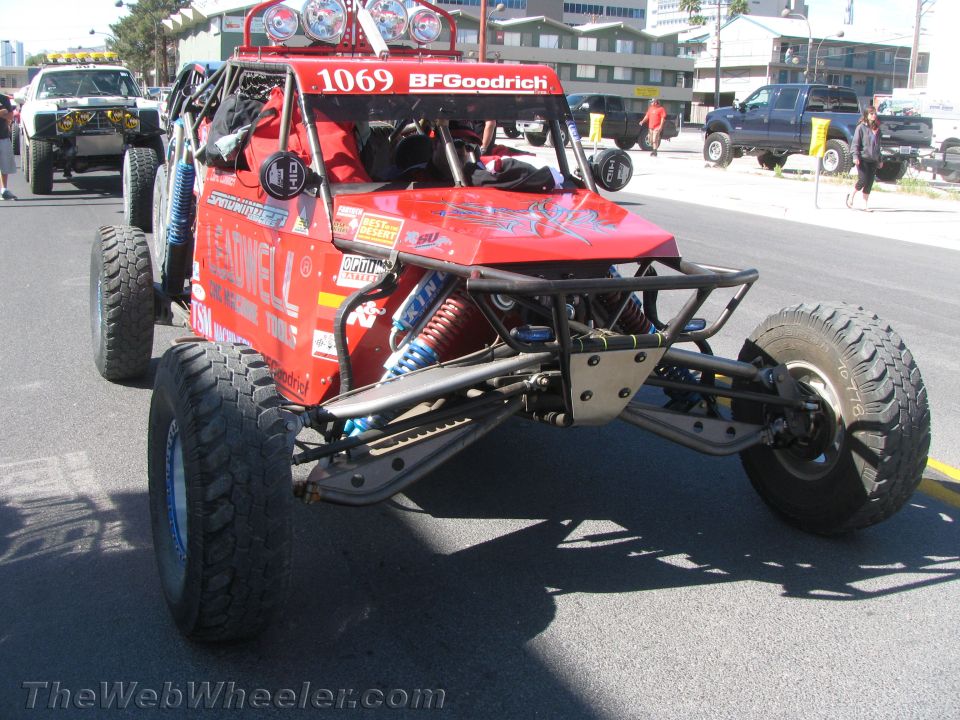 Red tube-chassis off-road buggy number 1069 with light bar on a street