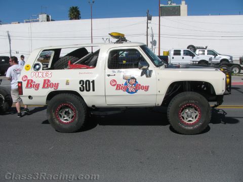 1990 Ford Bronco - Side view of a white off-road race truck numbered 301 with red Big Boy and Pike's restaurant graphics on a sunny street.