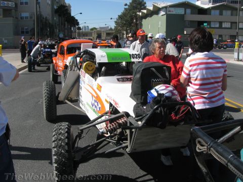 1990 Ford Bronco - white off-road race buggy numbered 1020 sits on a city street as people in casual clothing stand nearby looking on.