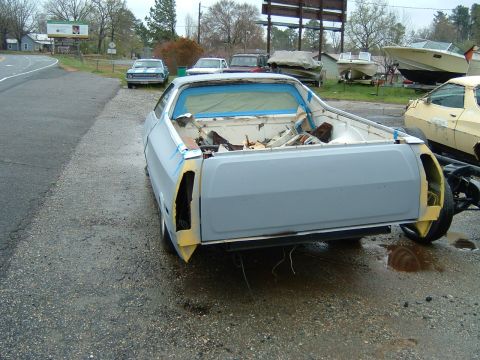 1979 Ford Ranchero - A 1979 Ford Ranchero in primer is parked outdoors, showing its rear end with blue masking tape on the windows.