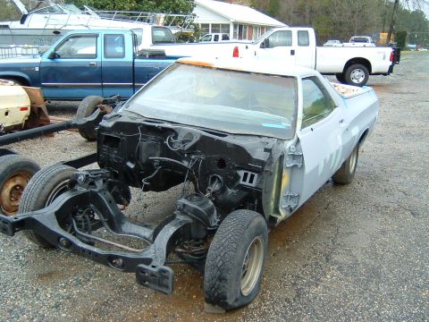 1979 Ford Ranchero - A 1979 Ford Ranchero body sits on its chassis, awaiting restoration, with other vehicles in the background.