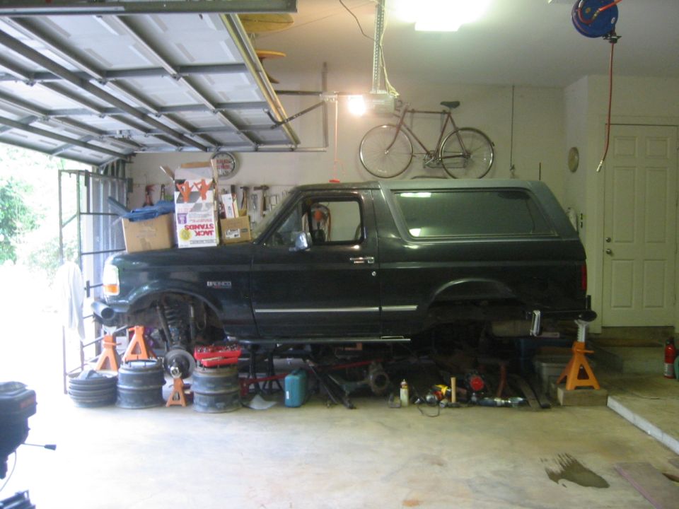Black Ford Bronco on jack stands in a garage being worked on