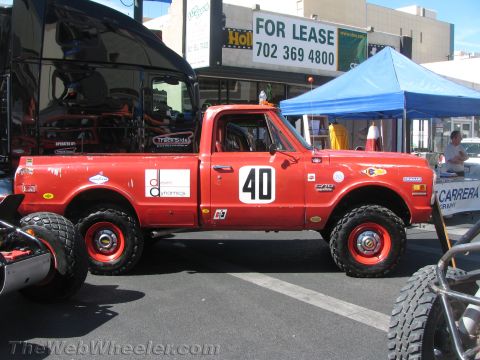 1990 Ford Bronco - red vintage Chevrolet pickup race truck numbered 40 with red wheels sits beside a For Lease sign and a blue canopy.