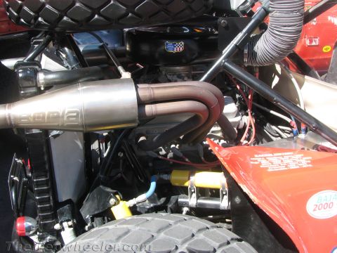 1990 Ford Bronco - close-up shows a stainless Borla muffler and exhaust headers tucked into the engine bay of a red off-road buggy.