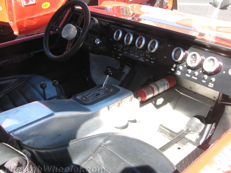 Interior of an off-road buggy showing steering wheel, gauges and shifter