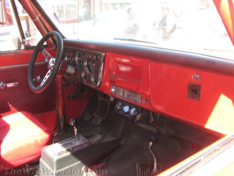 1990 Ford Bronco - bright red interior of a vintage pickup shows its dashboard, round gauges, bench seat and a floor-mounted shifter.