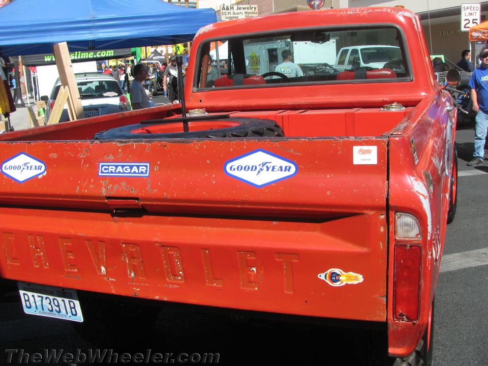 Rear tailgate of a weathered red Chevrolet pickup with Goodyear and Cragar stickers