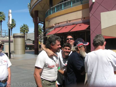 1990 Ford Bronco - cheerful group of men pose with arms around each other on a plaza outside a building with a Jewelers sign and red awning.