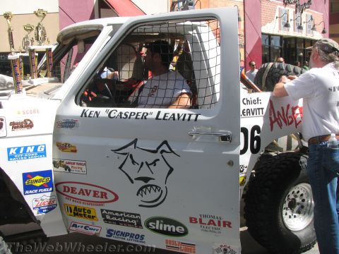 1990 Ford Bronco - open mesh-windowed door of a white race truck reading Ken Casper Leavitt, covered in sponsor decals including Deaver and Slime.