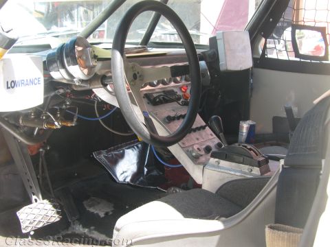 1990 Ford Bronco - stripped interior of an off-road race truck showing a black steering wheel, aluminum dash, shifter and a Lowrance navigation unit.