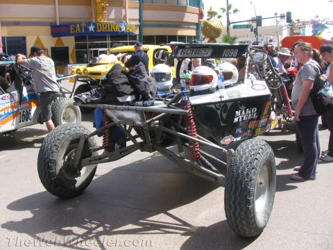 1990 Ford Bronco - black tube-frame off-road buggy numbered 1098 with Mako Steel branding and coilover shocks parked among spectators at a street event.