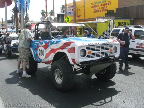 1990 Ford Bronco - early white Ford Bronco off-road race truck numbered 304, painted with red and blue stars-and-stripes graphics, on a Las Vegas street.