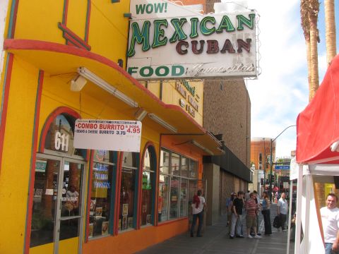 1990 Ford Bronco - yellow-and-orange restaurant storefront with a neon sign reading WOW Mexican Cuban Food, advertising combo burritos, with people walking by.