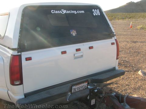 1990 Ford Bronco - Rear view of a white pickup with a camper shell lettered Class3Racing.com and 306, showing California plate 7K98906 in the desert.