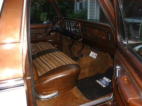 1978 Ford Bronco - The interior of a 1978 Ford Bronco features striped upholstery and wood-grain trim on the dashboard.