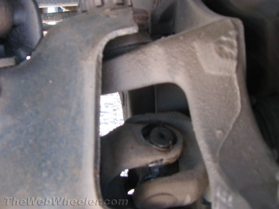 Close-up of a steering shaft U-joint and steering knuckle under a vehicle