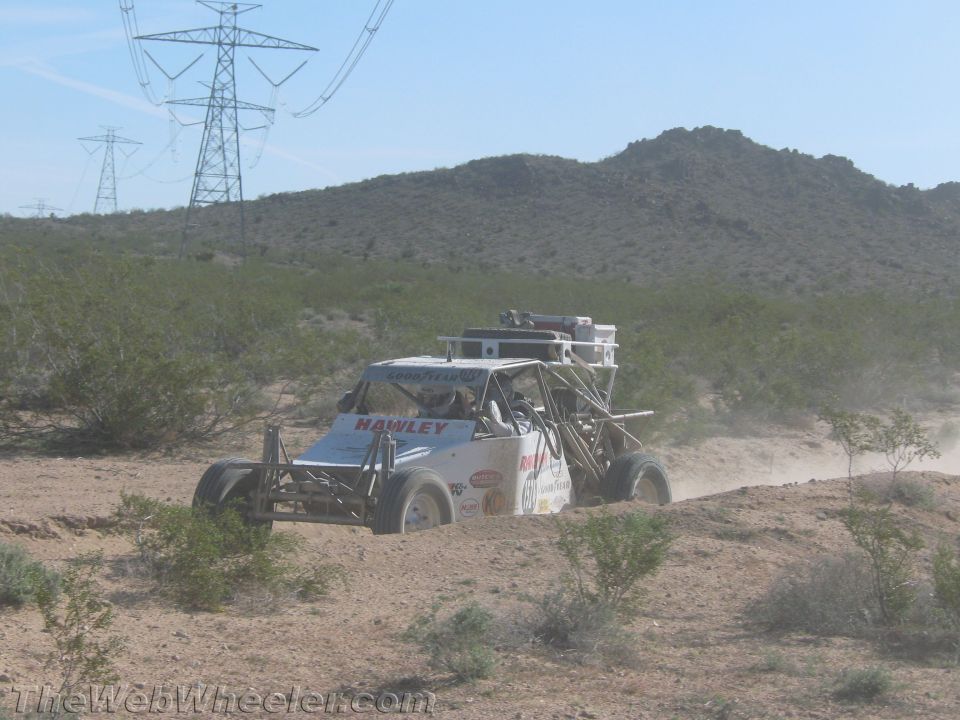 White off-road race buggy kicking up dust on a desert trail