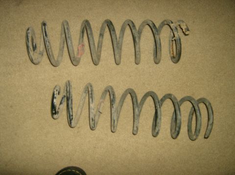 2004 Jeep Wrangler - Two used coil springs are shown against a neutral background, with one exhibiting damage.