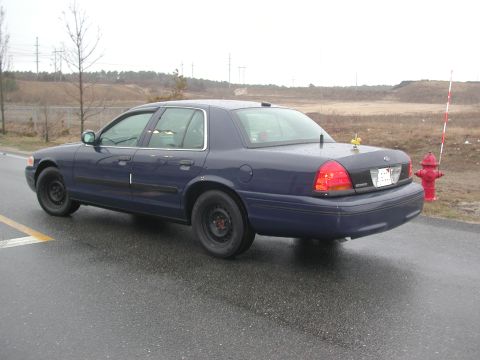 1999 Ford Crown Victoria - Rear view of a dark blue 1998 Ford Crown Victoria sedan parked on a wet road.