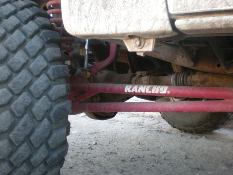 1993 Ford Bronco - Close-up view of the undercarriage, showing a large tire and red Rancho steering components.