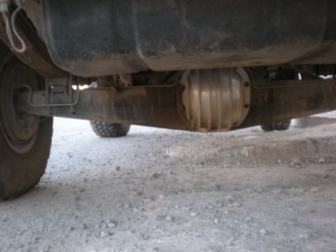 1993 Ford Bronco - The underside of a vehicle shows the rear axle assembly and a large fuel tank above it.