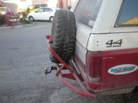 1993 Ford Bronco - Rear view of a red and white SUV, a spare tire on the back and a '4x4 OFF ROAD' decal.