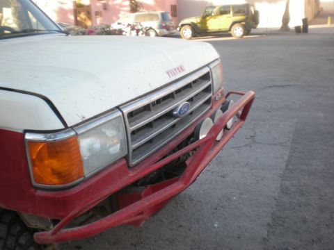 1993 Ford Bronco - This Ford F-Series truck features a prominent grille and aftermarket bumper, with a Jeep visible in the background.