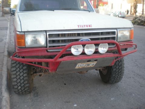1993 Ford Bronco - Front view of a white Ford Bronco with a red bull bar and fog lights.