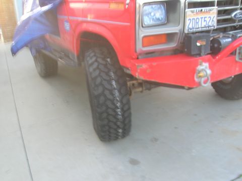 1985 Ford Bronco - Front view of a red Ford Bronco with off-road tires and a custom bumper.