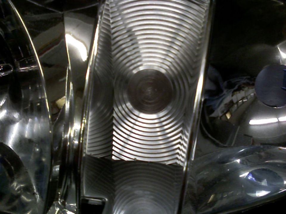 Close-up of a headlight's chrome reflector and ribbed fresnel lens optics