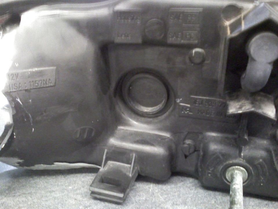 Back of black headlight housing showing bulb cap, SAE markings and 1157NA bulb label