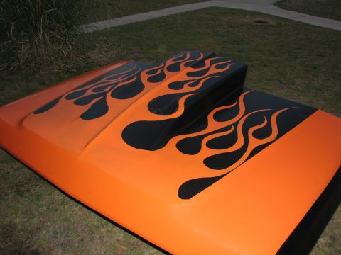1979 Ford Bronco - A freshly painted orange hood with a raised cowl scoop, laid on a lawn and finished with sprayed black tribal flame graphics that flow back…