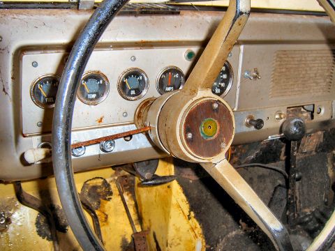 1966 International Scout 800 - The interior of an older vehicle shows a dashboard with multiple gauges and a worn steering wheel.