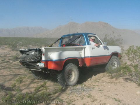 1990 Ford Bronco - Rear three-quarter view of a red, white and blue lifted Dodge 4x4 pickup with a spare tire on the tailgate.