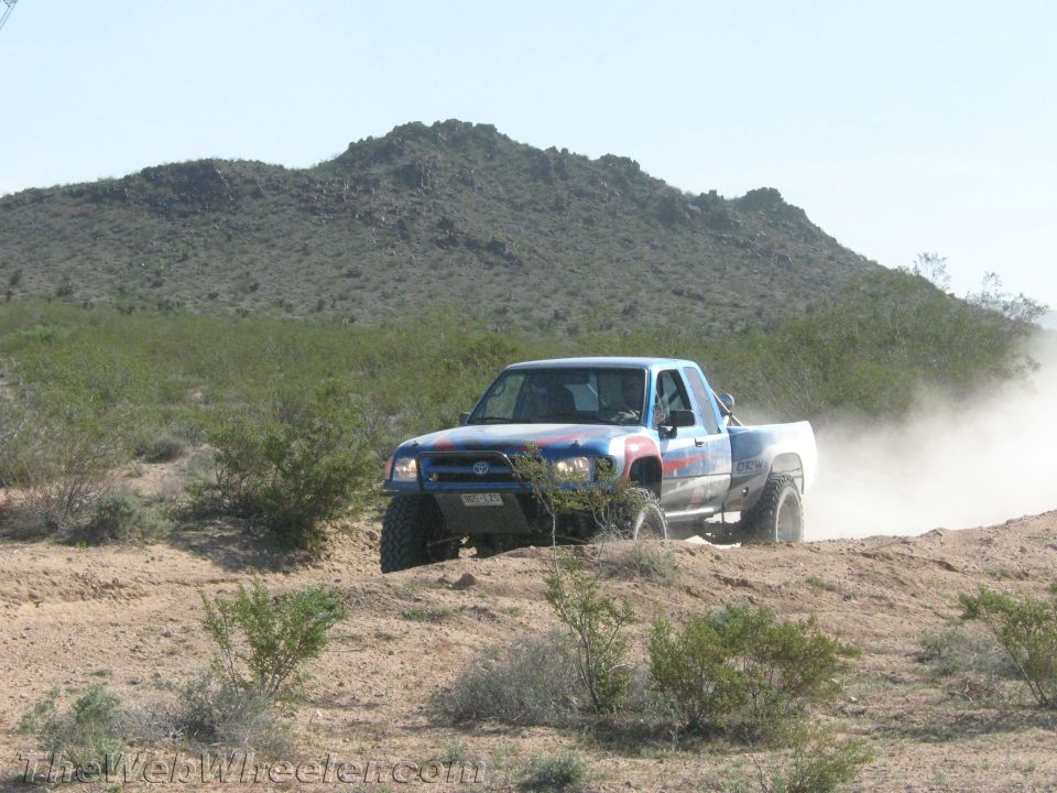 Lifted Toyota pickup truck racing across desert terrain