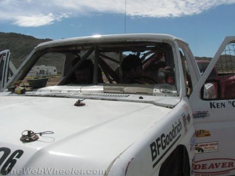 1990 Ford Bronco - Close view of the windshield, roll cage and BFGoodrich-decaled hood of a white off-road race truck in the desert.