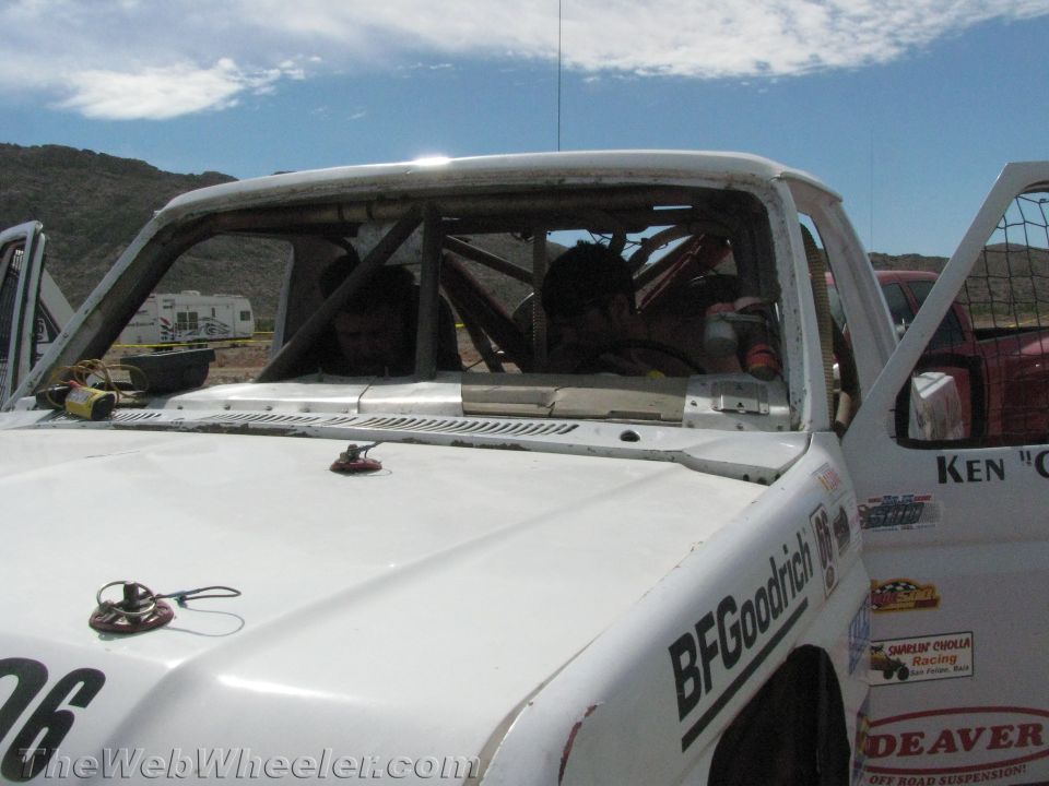 Close-up of windshield and roll cage of white off-road race truck with sponsor decals