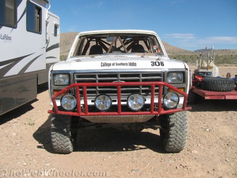 1990 Ford Bronco - Front view of a white off-road race truck numbered 306 with a red tube bumper, quad lights and College of Southern Idaho lettering.