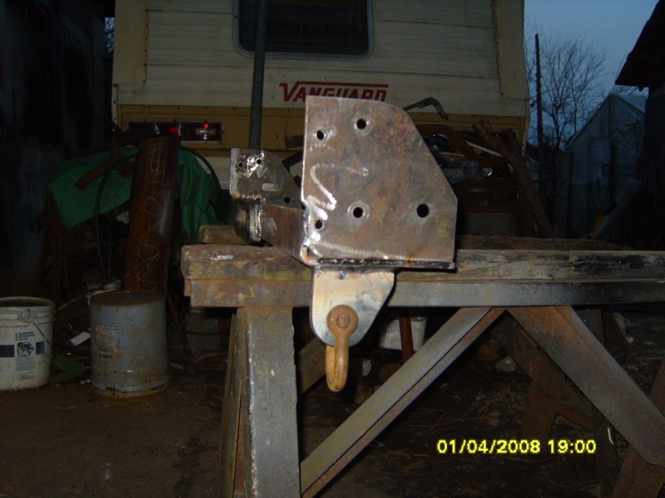 Winch mount bracket with multiple bolt holes and a tow hook, resting on a metal stand