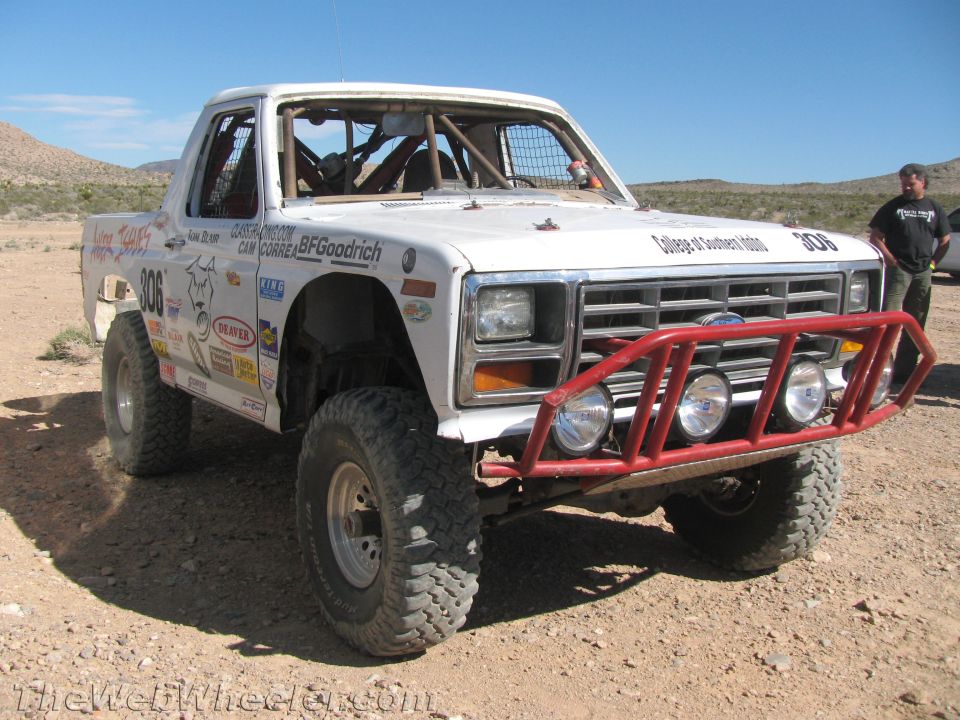 White Ford off-road race truck #306 with red bumper on desert ground