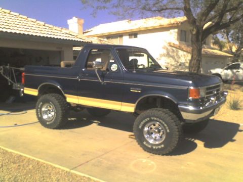 1991 Ford Bronco - This lifted Ford Bronco is parked in a driveway in front of a house.