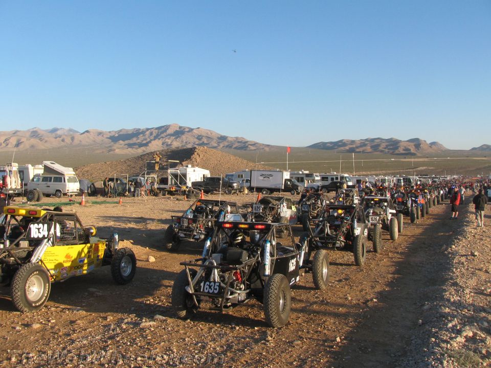 Rows of off-road race buggies lined up at a desert staging area
