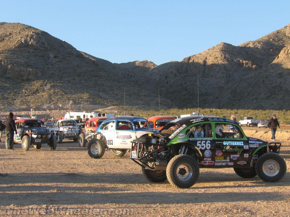 Green VW-based off-road buggy #556 and other cars staged in the desert