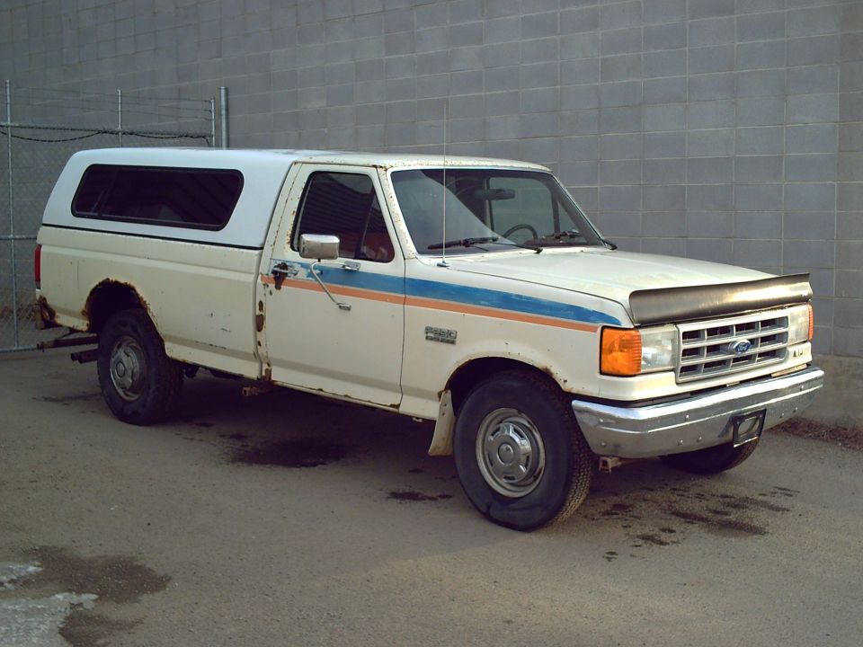 1990 Ford F-250 pickup truck with a white camper shell, parked outside
